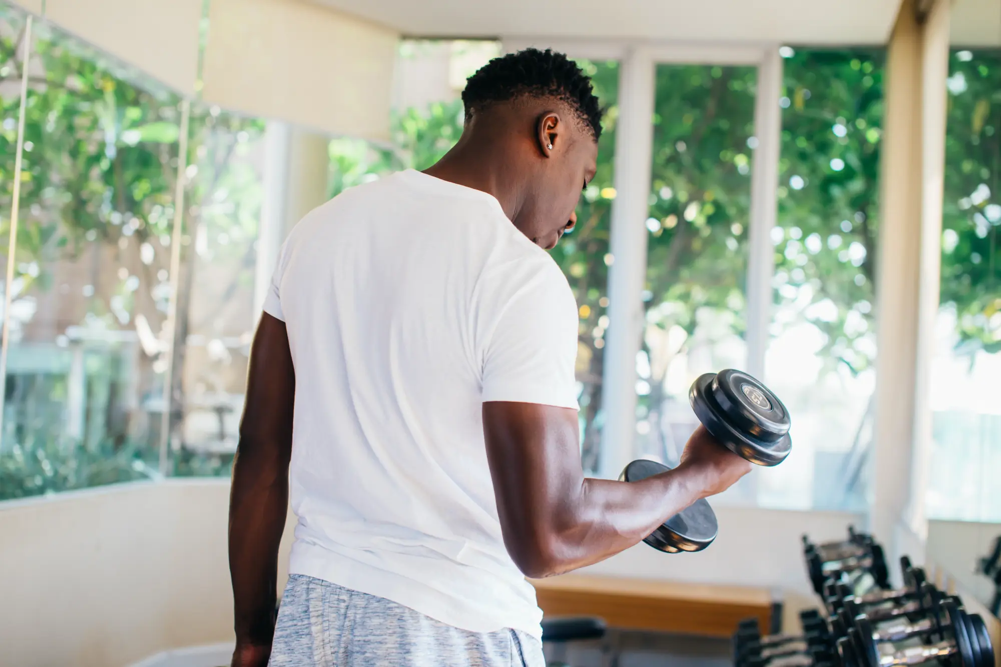 Man working out in the gym doing bicep curls with mild elbow pain